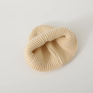 Dettaglio del cappello in maglia beige chiaro per neonati con trama a costine