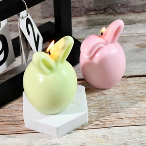 Charming rabbit-shaped Easter candles in pink and green colors lit for cozy home decor