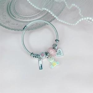 Detail von Silberarmband mit rosa Perlen, Herzanhänger und niedlichem Bären-Anhänger