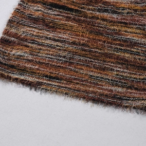 Détail macro du tissu pelucheux rayé avec motifs ethniques et pompons à franges