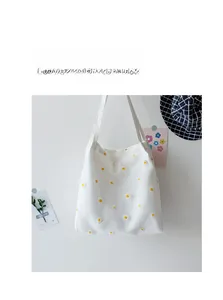 Detail of white canvas tote bag with delicate embroidered yellow daisy patterns