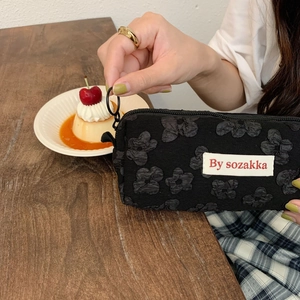 Detailed macro of black floral textured pouch with a branded woven label on a table