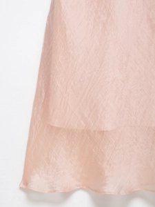 Detail of pink semi-transparent textured fabric with elegant pleated midi dress ruffles