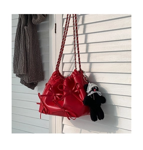 Detail view of red PU leather bag with 3D bows and woven chain shoulder strap