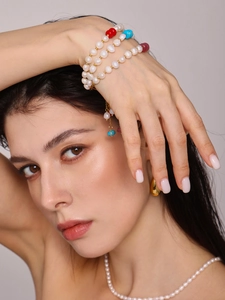 Gros plan d'un bracelet en perles d'eau douce multicouches avec glands en pierre colorés