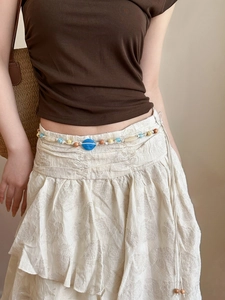 Détail de la chaîne de taille bohème avec perle en résine bleue et billes de bois