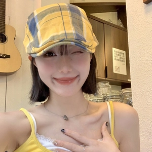 Casquette gavroche vintage à carreaux jaune et bleu pour femme dans un décor de café
