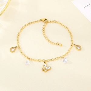 Detail of gold butterfly and teardrop charms with clear stones on a stainless steel anklet