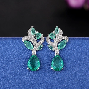 Macro detail of emerald teardrop earrings with silver metal and micro-set diamonds