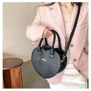 Vue détaillée du sac cœur noir à motif crocodile avec logo Fllora doré et poignées