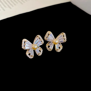 Detailed view of butterfly earrings with sparkling cubic zirconia and light gold pearls