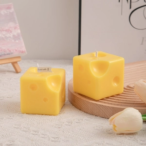 Realistic yellow cheese shaped scented candle on a wooden tray with floral decor