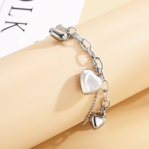 Macro detail of silver titanium steel double-layer bracelet with three heart pendants