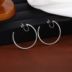 Macro view of polished silver metal hoop clip-on earrings for non-pierced ears