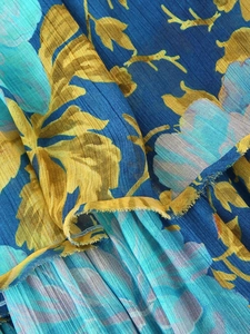 Close-up of pleated chiffon fabric with turquoise floral print on navy blue background