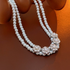 Close-up of double-layer pearl choker necklace featuring floral rhinestone pendants