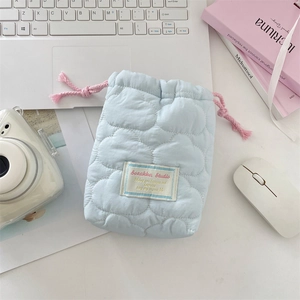 Close-up of soft blue quilted camera pouch with pink drawstring and aesthetic brand label