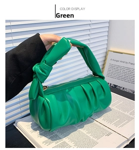 Close-up of green pleated cloud bag featuring knotted handle and gold zipper detail