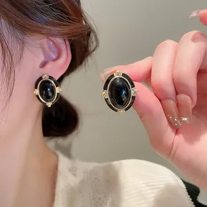 Detail of vintage French style oval black earrings with gold trim on model ear