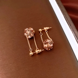 Macro detail of rose gold dangle earrings with pavé crystal spheres on leather