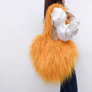 Side view of large orange fluffy faux fur heart shaped crossbody bag on female model