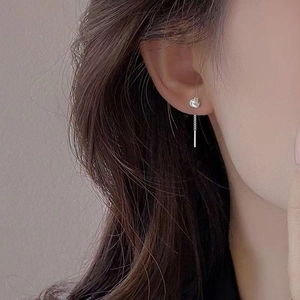 Close-up of long silver tassel earrings with round knot and bar on female model
