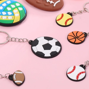 Set of colorful PVC sports ball keychains including soccer and basketball on pink background
