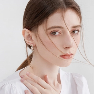 Elegant C-shaped woven pearl stud earrings with metallic gold base on female model