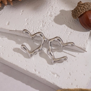 Detail of silver heart hoop earrings with a fluid melting texture on a stone background