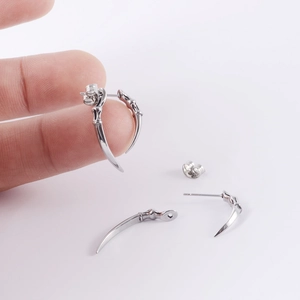 Detailed view of silver stainless steel spike earrings held for size reference