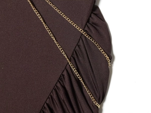 Detail of dark brown knitted fabric with elegant gold chain and side ruching design