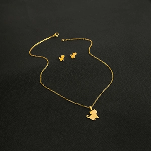 Detail of golden stainless steel cat pendant necklace and earrings set on black surface