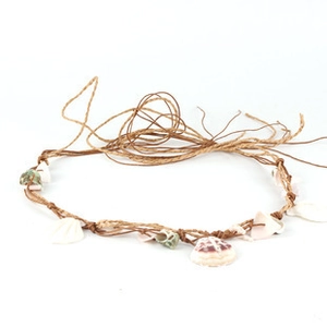 Detail of bohemian braided brown jute rope with natural shells for hats or belts