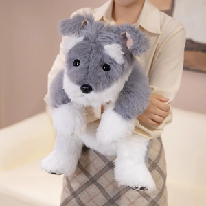 Lifelike gray and white Schnauzer plush toy held by a model in a warm home setting