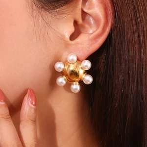 Detailed view of 18K gold plated wheel earring with pearls worn on model ear
