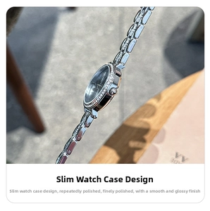 Macro side view of slim silver steel watch case with crystal-set bezel and crown