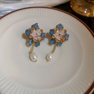 Detail of blue flower earrings with white pearls and pink crystals on ceramic plate