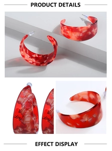 Macro detail of C-shaped red marble texture acrylic hoop earrings on a modern display