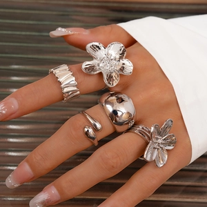 Detail showing five-piece silver geometric flower ring set worn on female fingers