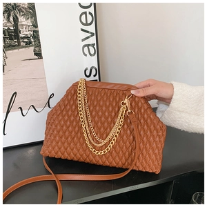 Detail of a brown pleated PU leather evening bag with golden metal chains on black surface