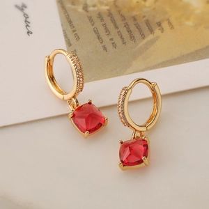 Dettaglio ravvicinato di orecchini placcati oro con gemme rosse e accenti in zircone