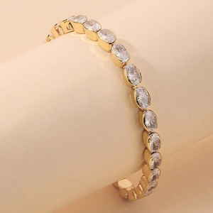 Detail shot of a gold-plated tennis bracelet featuring oval-cut cubic zirconia stones