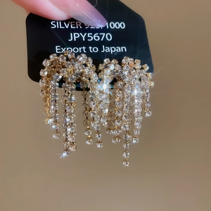 Close-up of sparkling gold tassel earrings with s925 silver needles and crystals