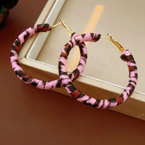 Makro-Detail von Creolen mit Leopardenmuster, rosa Textur und goldenen Stiften