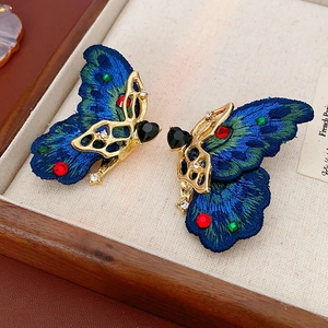 Vue macro de boucles d'oreilles papillon vintage avec broderie et pierres colorées