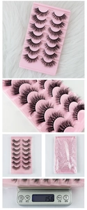 Macro detail of 7 pairs of thick black synthetic false eyelashes in a pink tray