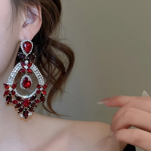 Detail of elegant silver needle drop earrings with red gemstones and sparkling rhinestones