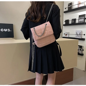 Model view of pink quilted shoulder bag with silver chain strap and heart ornament