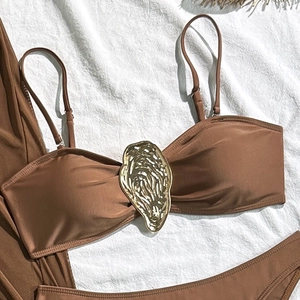 Detailed view of dark brown bikini top with decorative gold oyster shell buckle