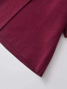 Close-up of the fine texture and hem stitching on the burgundy knit short sleeve cardigan